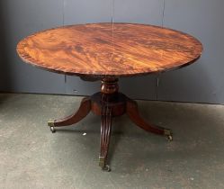 A Regency mahogany circular tilt-top breakfast table, raised on four swept legs with brass caps