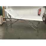 A folding white vinyl massage table by SkinMate