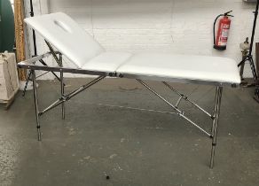 A folding white vinyl massage table by SkinMate