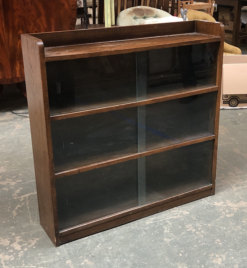 An oak bookcase with three shelves and glass sliding doors, 91cmW