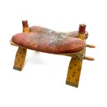 A camel stool with fitted red leather cushion, 72cmW
