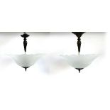 A matched pair of milk glass and patinated metal ceiling lights, each with three fittings, 44cmD