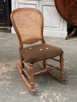 A small rocking chair with caned back, turned stretcher and stuffover seat