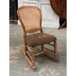 A small rocking chair with caned back, turned stretcher and stuffover seat