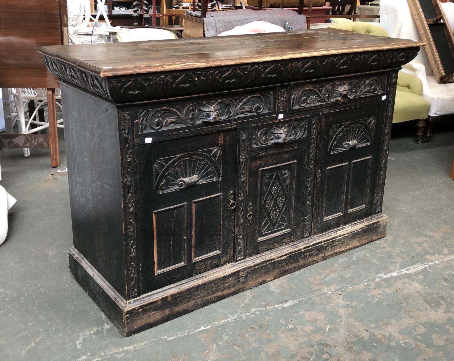 A carved oak sideboard, two drawers over central drawer and cupboard, flanked by two further