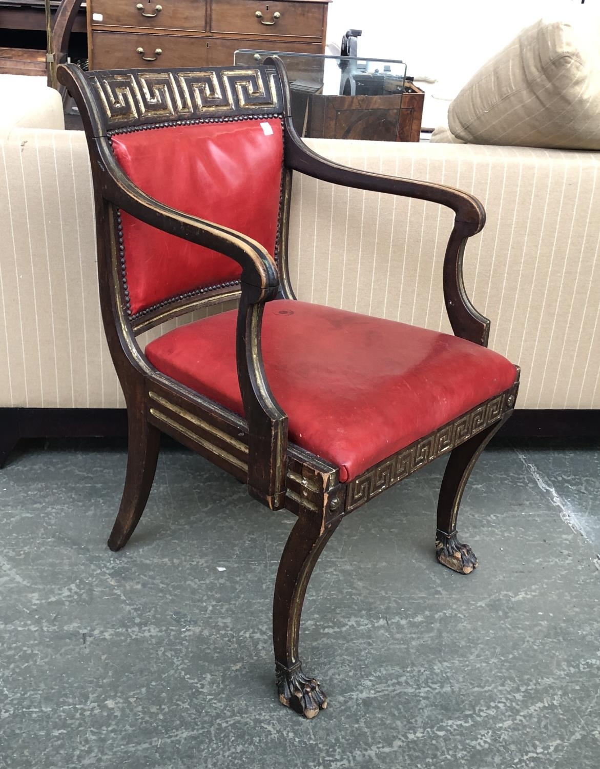 A Regency open armchair, the curved toprail with gilt Greek key motif, above a close nailed red