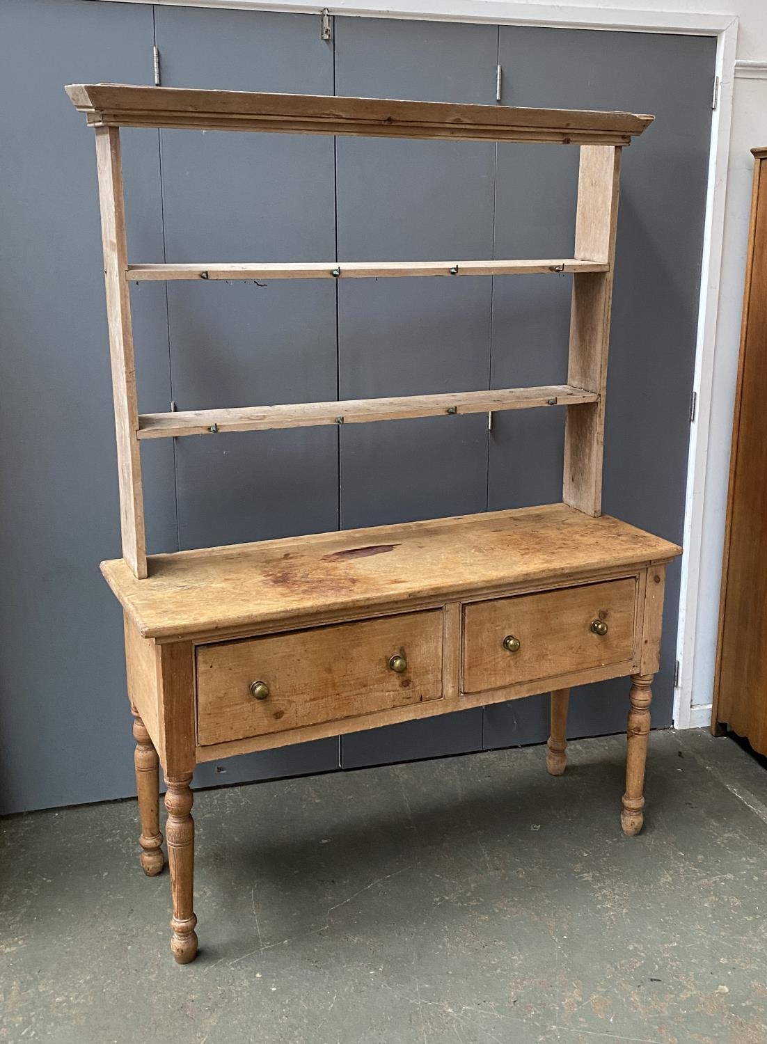 A 19th century pine kitchen dresser, the rack with two shelves, over a base of two drawers, on