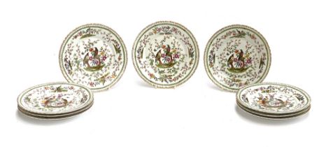 A set of nine early 20th century plates, decorated with birds in trees, heightened in gilt,