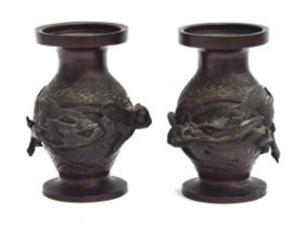 A pair of Japanese baluster form bronze vases depicting dragons clutching pearls in high relief,