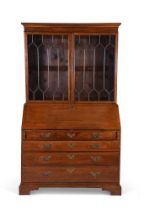 A George III oak bureau bookcase, the fall enclosing a fitted interior, over four graduating