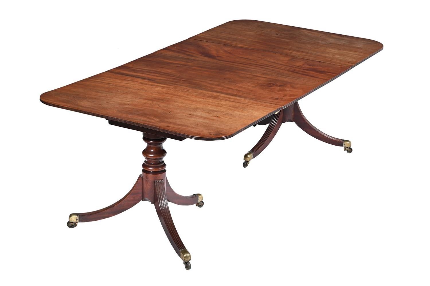 A Regency mahogany twin pedestal extending dining table, the turned column supports each on three