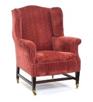 A wingback armchair in George III style, early 20th century, on square tapered legs joined by H