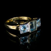 An 18ct yellow and white gold aquamarine trilogy ring, a central emerald cut aquamarine approx. 1.