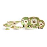 A 19th century hand painted dinner service, floral panels on a green ground, heightened in gilt,