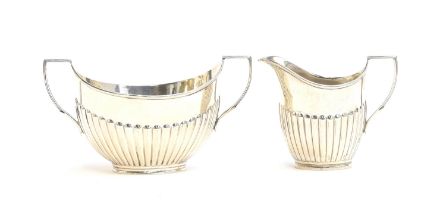 A silver George V milk jug and sugar bowl by William Hutton & Sons, London 1912, each with half