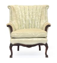 A scalloped barrel back armchair, with feather filled cushion, with carved outward scrolled arms, on