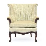 A scalloped barrel back armchair, with feather filled cushion, with carved outward scrolled arms, on