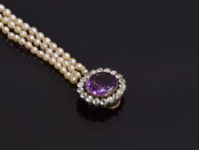 A graduated three row pearl necklace, with gold clasp, tests as 14ct or higher, set with a central