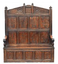 An 18th century and later carved oak high back settle, fleur de lis panels, over a hinged seat, with