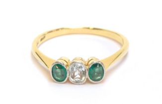 An early 20th century 18ct gold and platinum bezel set emerald and aquamarine trilogy ring, size P