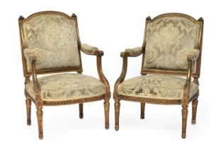 A very near pair of carved giltwood neoclassical open armchairs in Louis XVI taste, 62cm wide, the