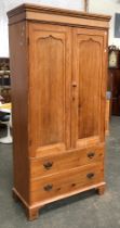 An early 20th century pine wardrobe of two panelled doors over two drawers, 106x49x214cmH