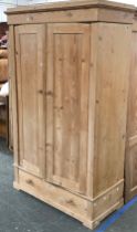 A pine wardrobe, the two panelled doors over a single drawer, 110x53x183cmH (in need of assembly)