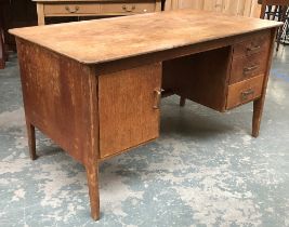 A mid century oak desk, kneehole flanked by three drawers and a cupboard, 138x76x76cmH
