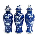 Three Chinese blue and white baluster vases and covers, prunus design, the covers surmounted by