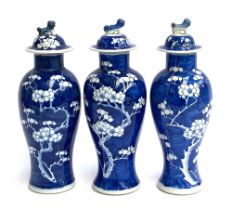 Three Chinese blue and white baluster vases and covers, prunus design, the covers surmounted by