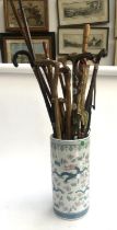 A Chinese ceramic stick stand decorated with dragons amongst flora, containing a quantity of walking