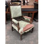 A carved oak armchair, floral detail to pediment top, upholstered in a green fabric, spindle