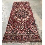 A Persian wool rug, blue and burgundy with central lozenge, approx 303x127cm