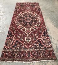 A Persian wool rug, blue and burgundy with central lozenge, approx 303x127cm