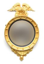 A Regency style gilt gesso convex mirror with carved eagle cresting, the circular mirror with