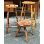 A 'rustic' style three legged milking stool, 36cmH; together with two kitchen stools, 69cmH and