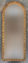A domed mirror with bevelled glass and scrolling frame, 113x46cm