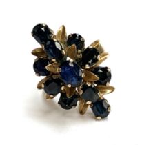 An 18ct gold dress ring set with sapphires in a floral setting, the head of the ring 2.8cmL, size N,