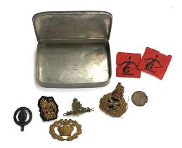 A tin containing military regimental badges, 'Malborough College Corps', Royal Navy artillery