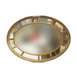 An early 20th century gilt gesso oval mirror, central bevelled plate, surrounded by eight further