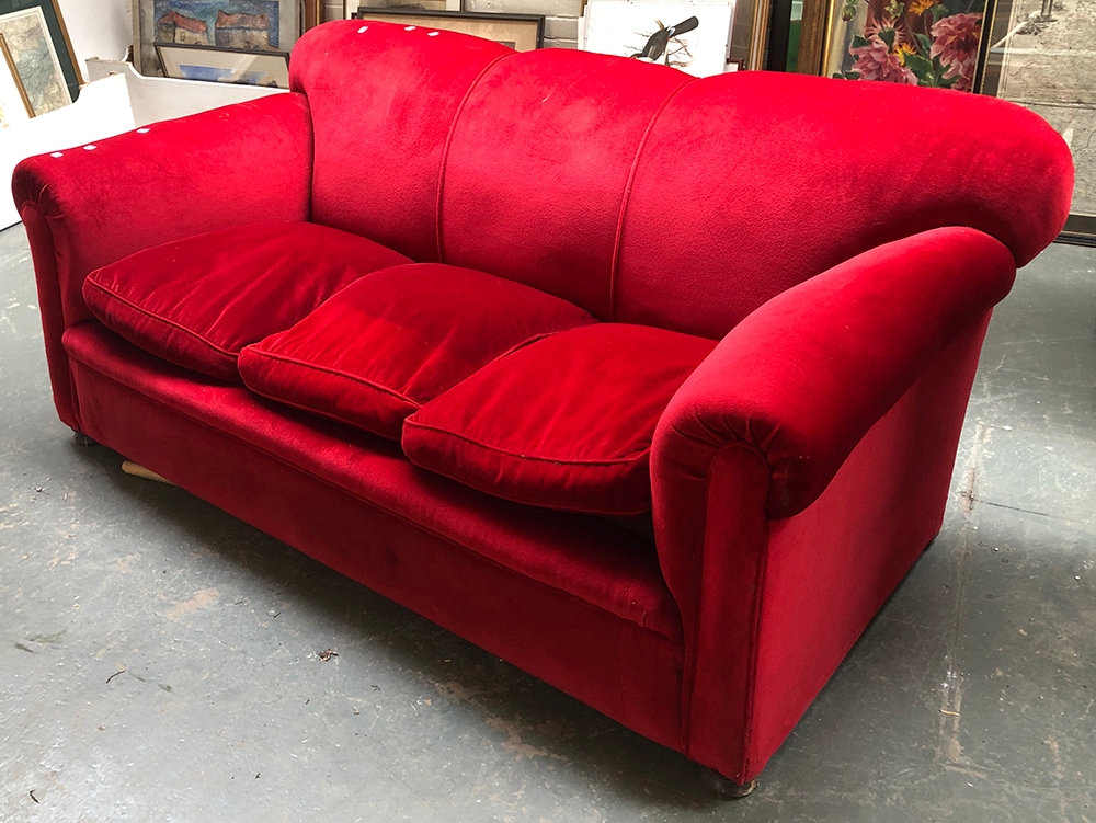 A large red velvet upholstered country house sofa, three feather filled cushions, on compressed