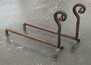 A pair of wrought iron fire dogs, 61cm long, 46cm high