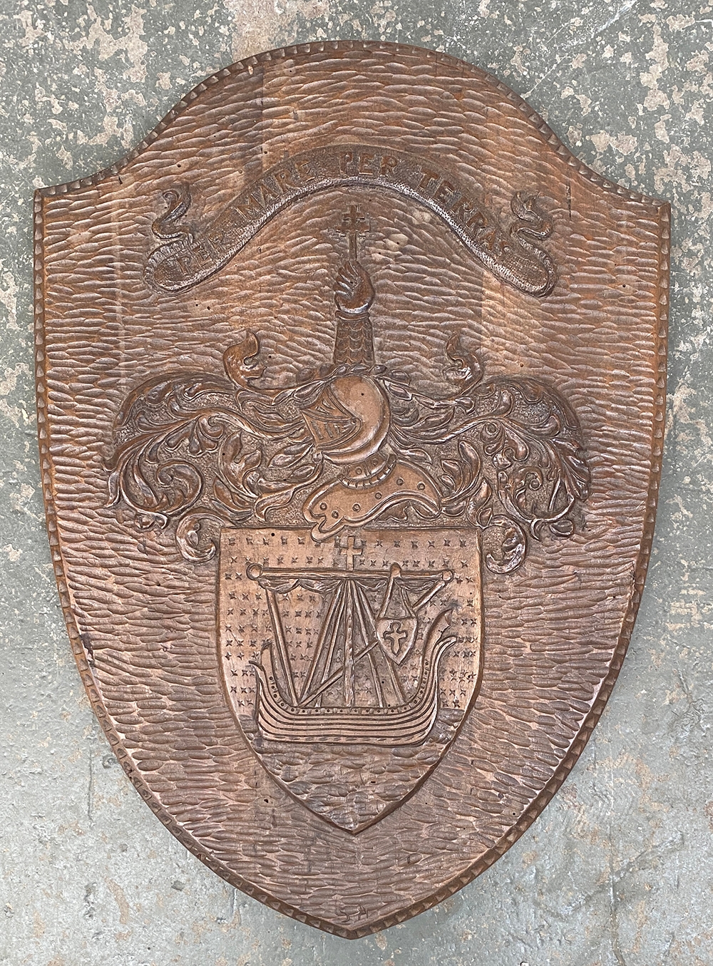 A carved shield plaque bearing the MacDonald crest with the motto per mare per terras, 67x48cm