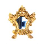 An early 20th century mirror with shaped plate in an ornate giltwood frame surmounted by a basket of