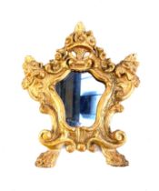 An early 20th century mirror with shaped plate in an ornate giltwood frame surmounted by a basket of