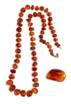 An amber bead necklace, the beads graduating from 0.6cm to 1.5cm wide, 64cm long unclasped, knotted,