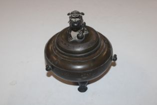 An Oriental bronzed censer and cover raised on three supports