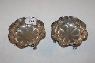 A pair of shaped silver dishes raised on four supp