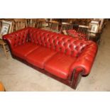 A red leather upholstered Chesterfield settee