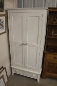 A white painted pine two door wardrobe fitted sing